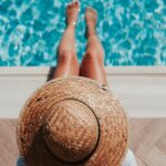 woman sitting on poolside setting both of her feet on pool